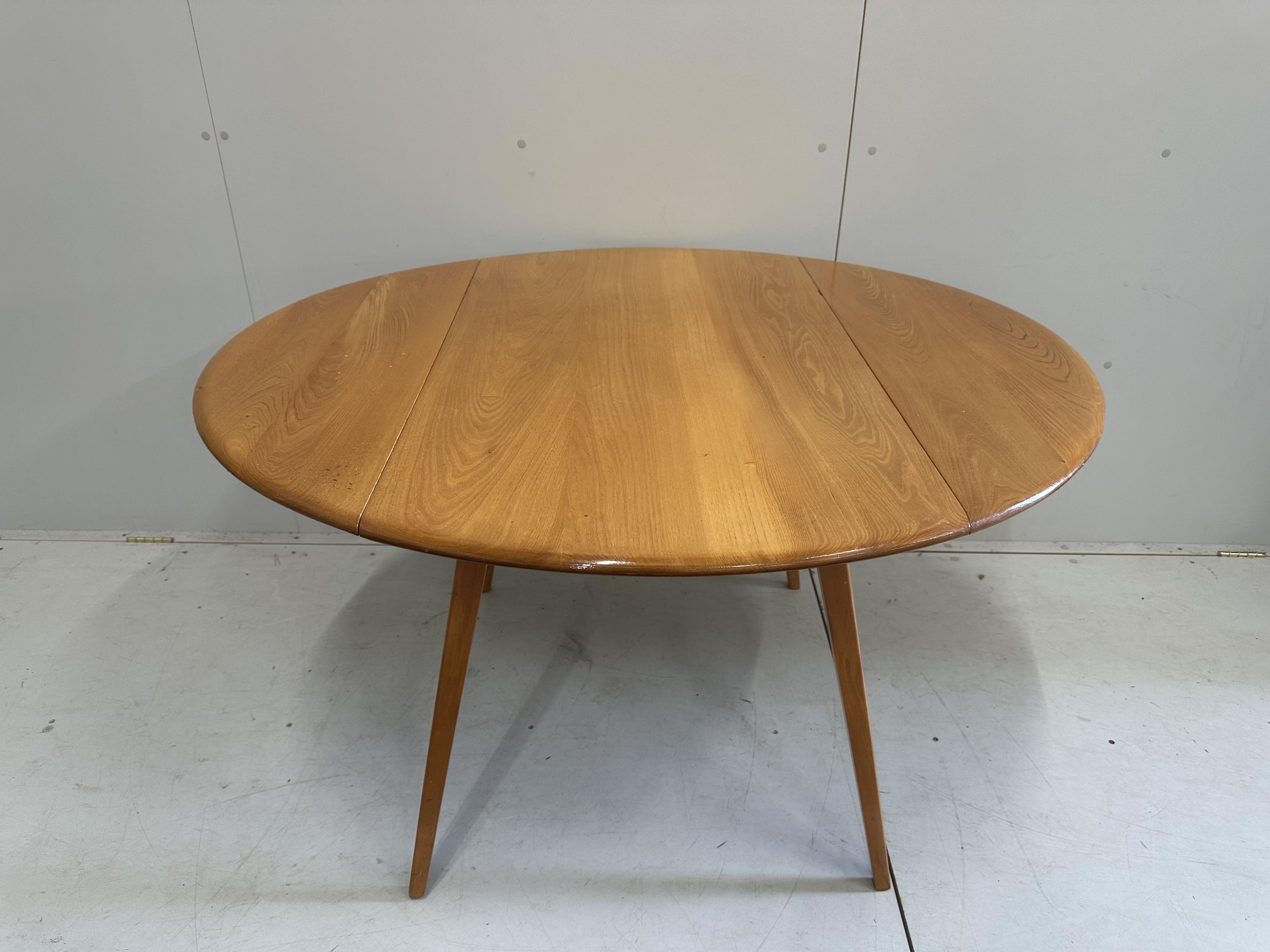 An Ercol elm oval drop leaf dining table, width 124cm extended, height 71cm, together with five Ercol elm, ash and beech dining chairs. Condition - fair to good